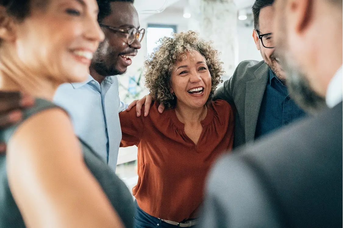 Group of office workers smiling together in a hug